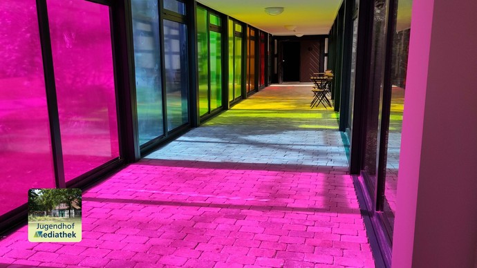 Das Foto zeigt den Sonnenlichteinfall durch die farbigen Fenster. Auch der Fußboden färbt sich durch das Licht regenbogenfarben.