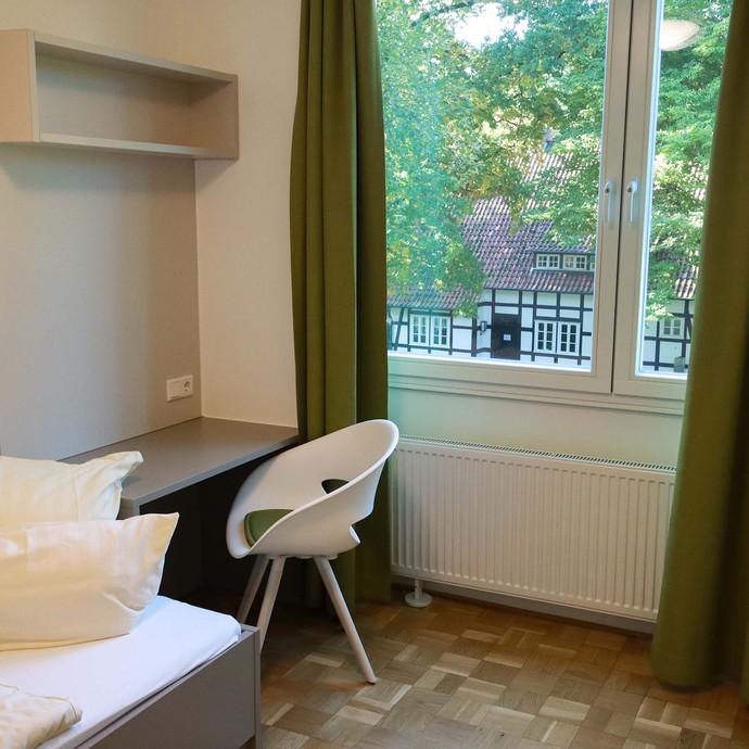 Foto: Gästezimmer mit Bett und Schreibgelegenheit (vergrößerte Bildansicht wird geöffnet)