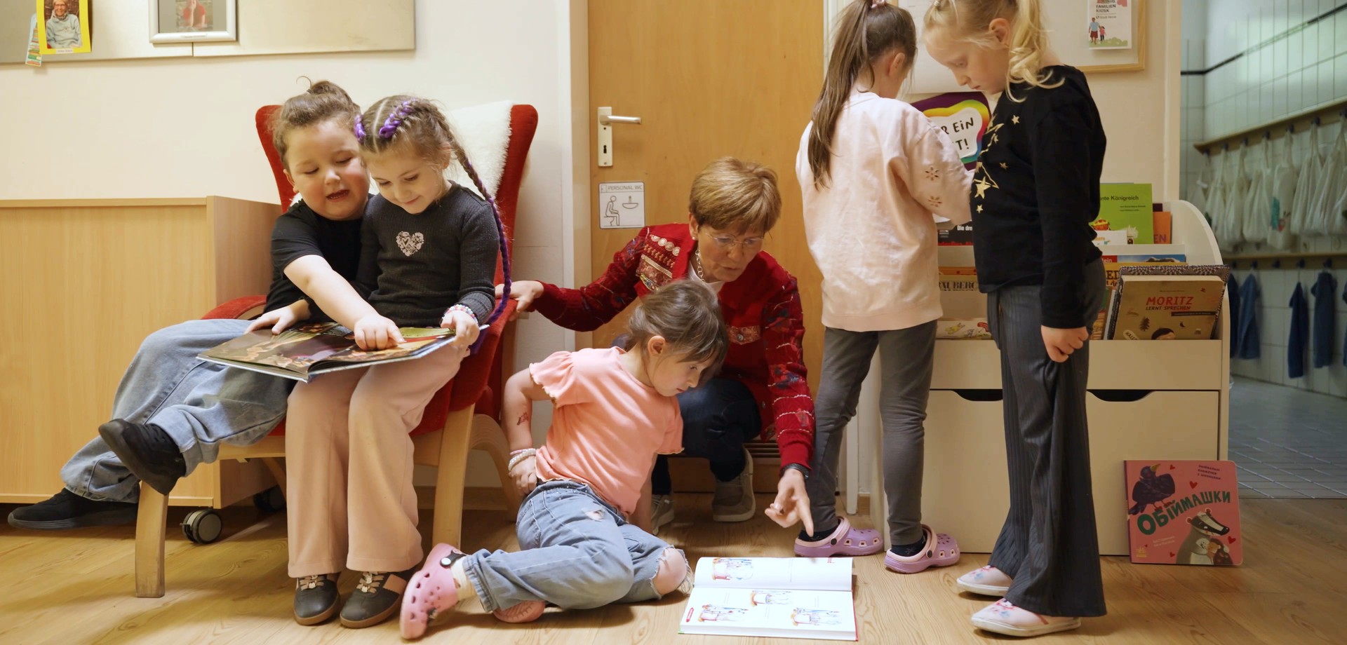 Eine Erzieherin und fünf Kinder lesen in Kinderbüchern