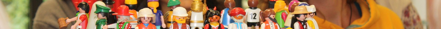 Das Foto zeigt Teilnehmende, die im Kreis stehen und eine Aufstellung mit Spiel-Figuren betrachten.